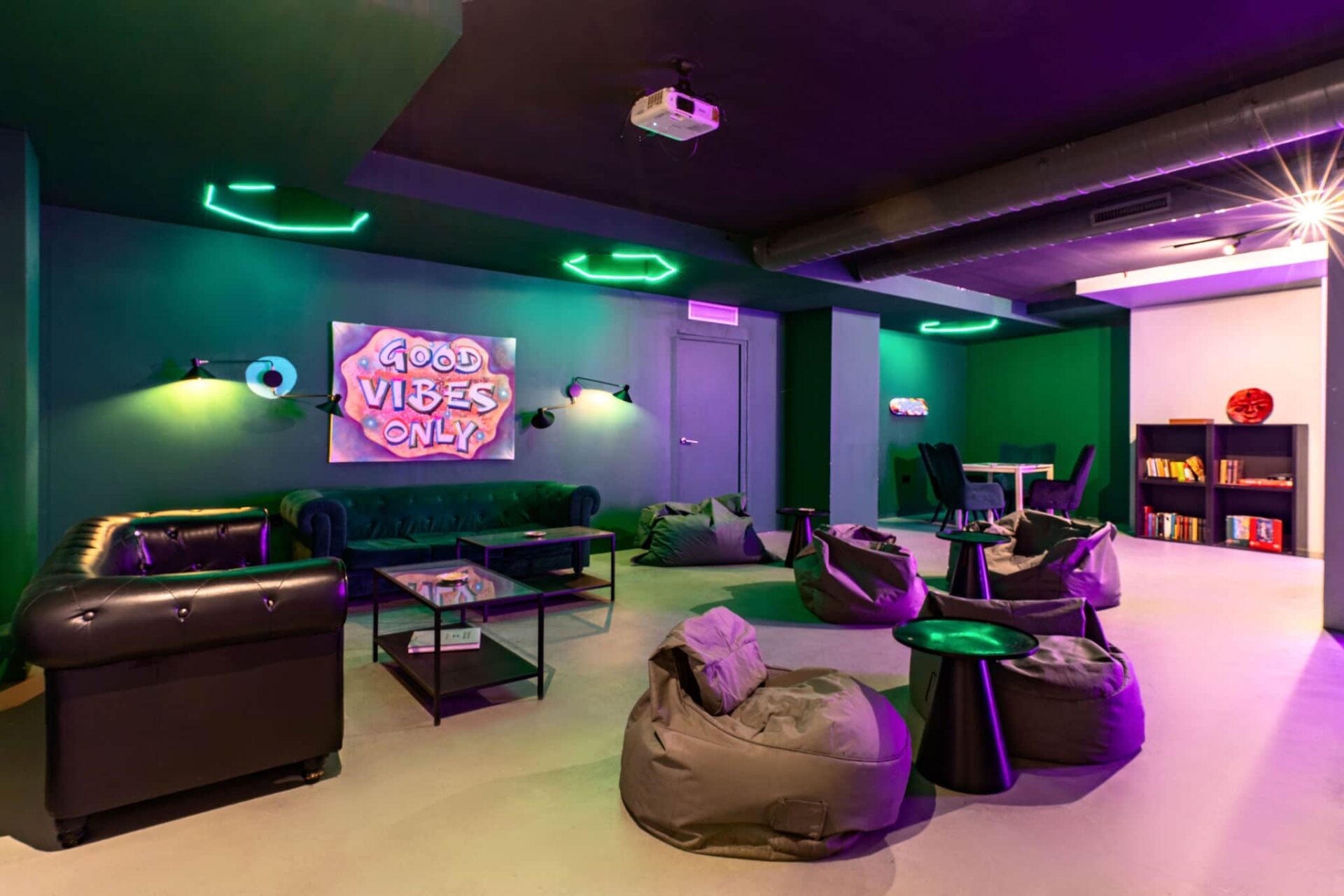 Zona lounge cómoda del club social cannábico Gusto Green en Barcelona con pufs y luces de neón