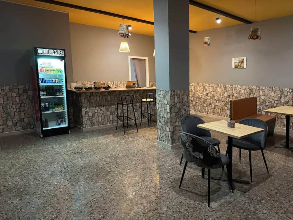 Interior del club de cannabis Magura en Valencia, con barra de piedra texturizada, suelo de terrazo, asientos modernos y nevera de bebidas.