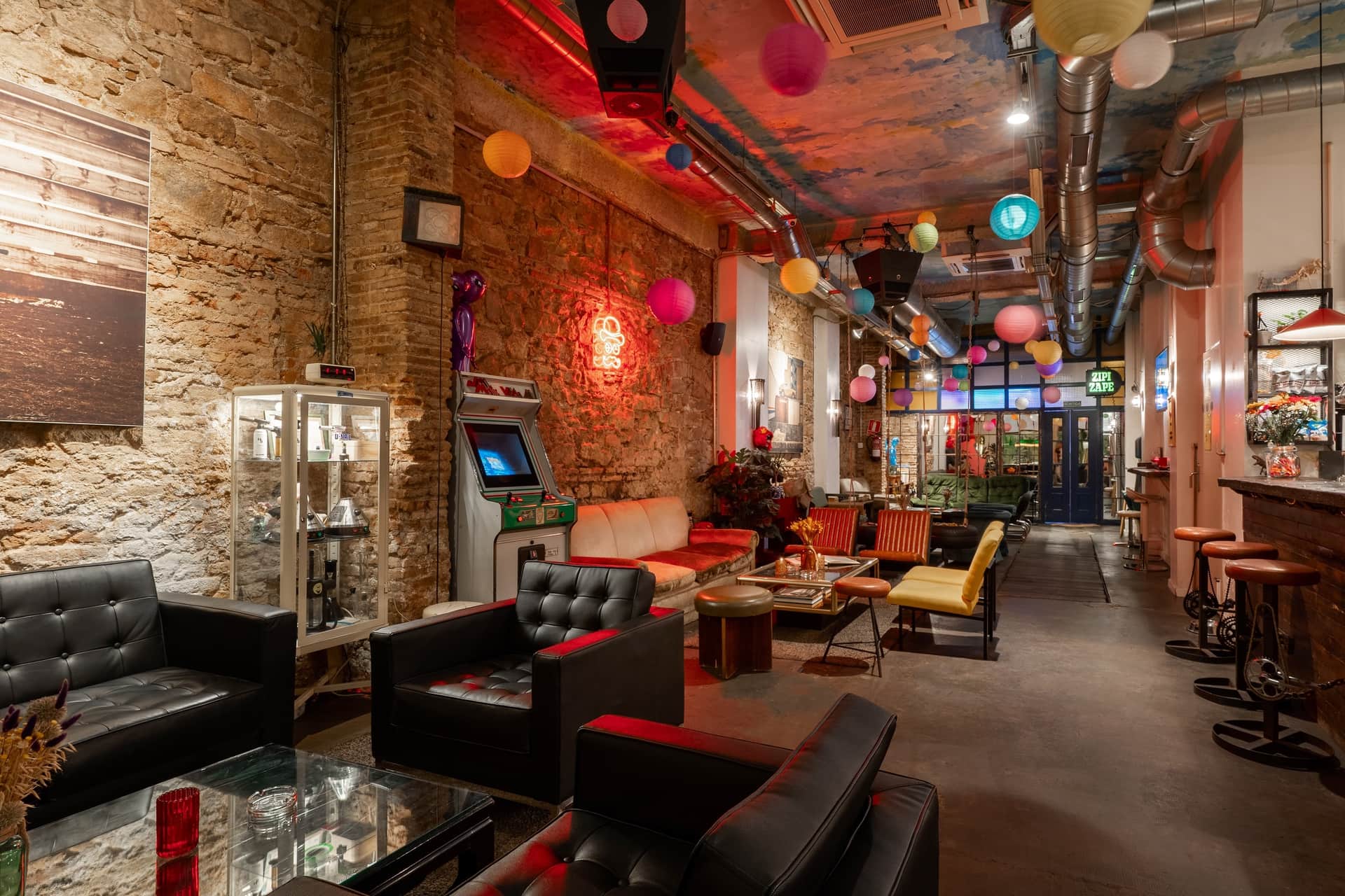 El club social cannábico Dr. Dou Barcelona — interior con sillones de cuero y máquina recreativa retro
