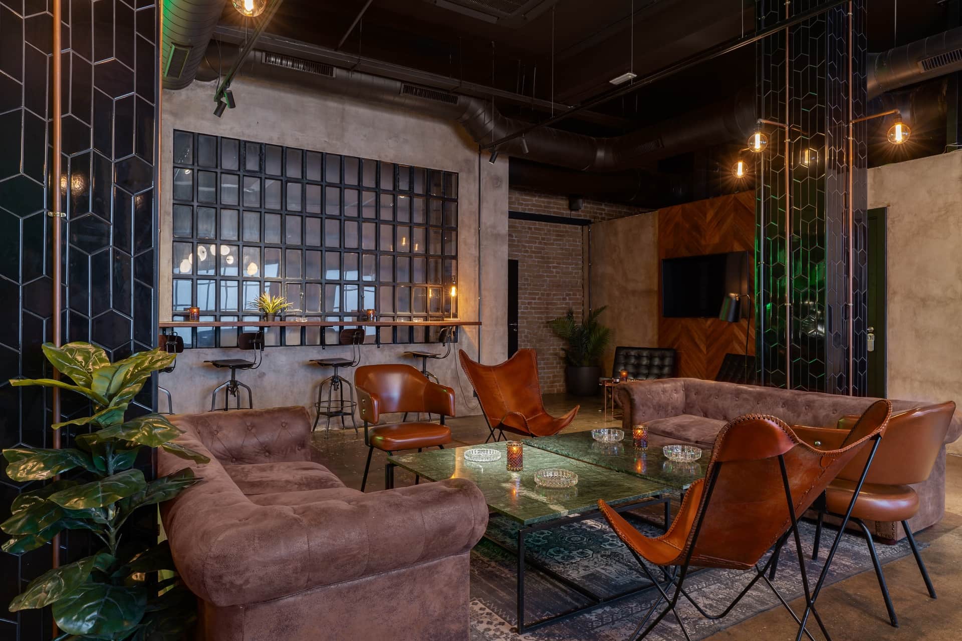 Dr. Resin Barcelona club social cannábico — lounge moderno con sofás marrones, mesas de cristal y plantas verdes