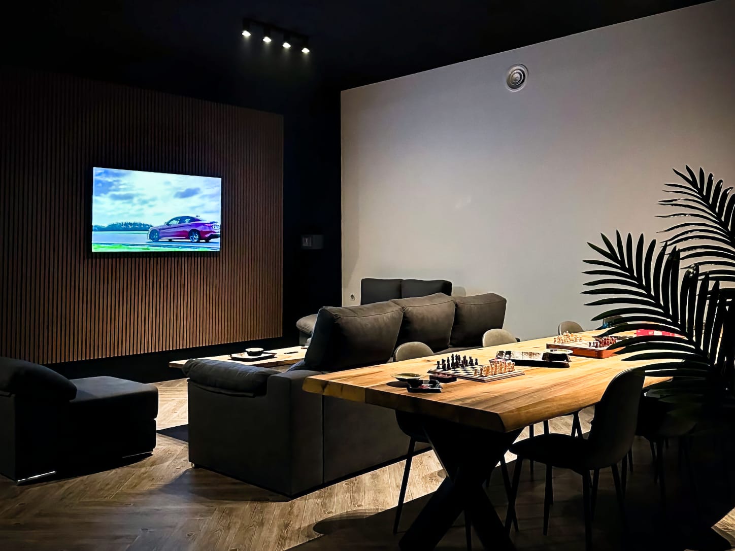 La acogedora zona chill-out del club de cannabis Four Twenty en Valencia, con sof&aacute;s oscuros frente a una gran pantalla de televisi&oacute;n en una pared de lamas de madera y tableros de ajedrez en una larga mesa de madera.