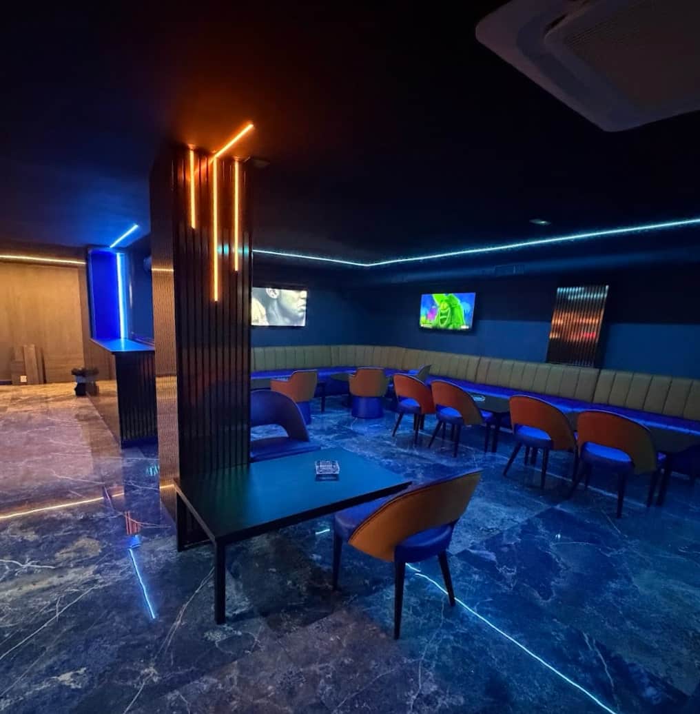Interior del social club Lux Lounge en Marbella con iluminaci&oacute;n ne&oacute;n azul, bancos tapizados y suelo de m&aacute;rmol.