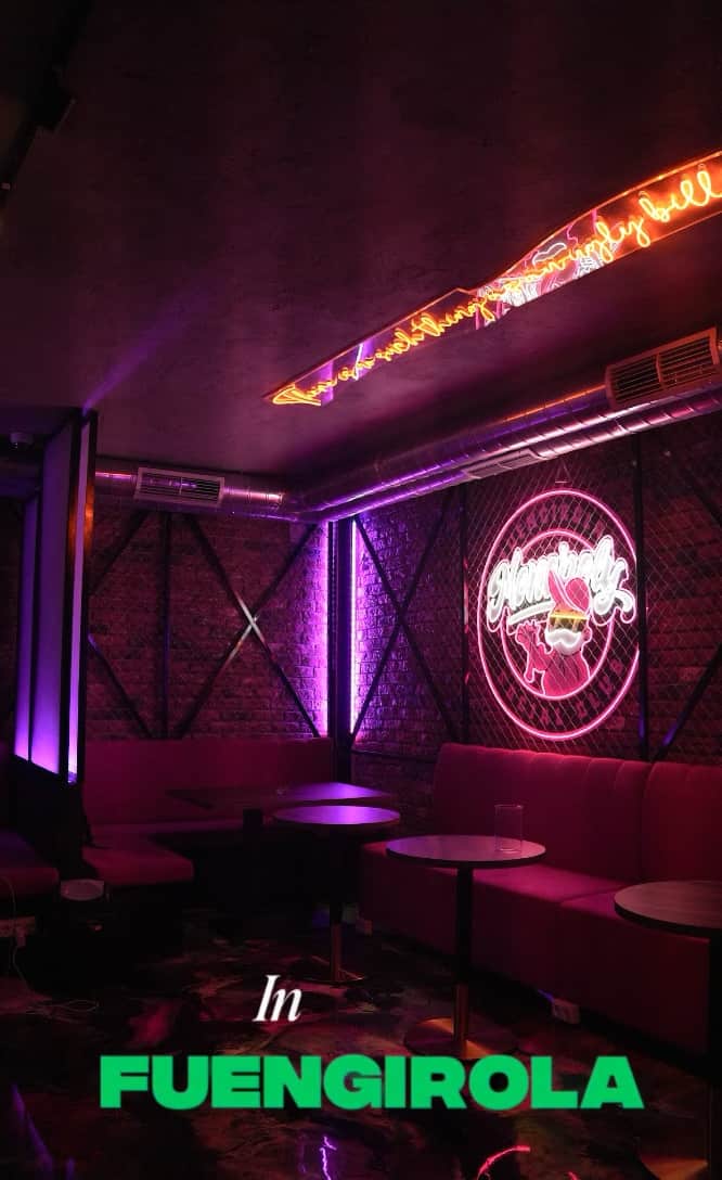 Preview de v&iacute;deo del Monopoly Social Club en M&aacute;laga, lounge con iluminaci&oacute;n ambiental rosa, pared de ladrillo, mesas redondas y sof&aacute;s rosas.