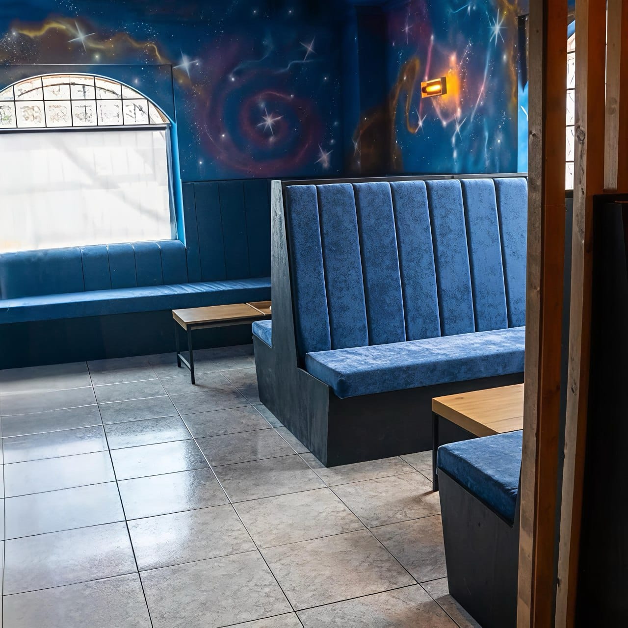 Zona lounge con bancos azules y mural espacial en Sky Alicante