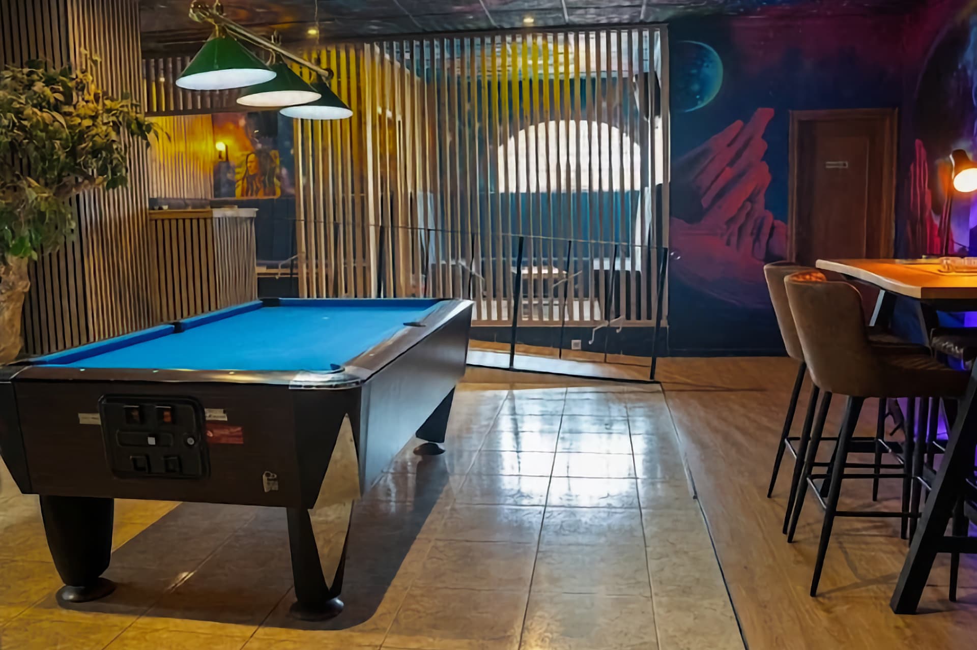 Mesa de billar en el club social cannábico Sky Alicante con mural espacial y separadores de madera